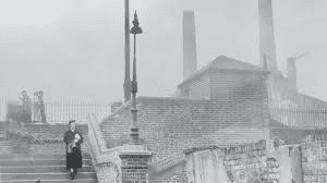 Side-by-side photographs of the same London street scene, showing normal visibility with clear building details and pedestrians on the left, contrasted with the same location during the Great Smog where thick, dark fog obscures buildings just meters away and people appear as ghostly silhouettes.